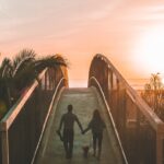 man and woman holding hand while walking on bridge in Florida