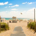 gray pathway leading to parasol, lifeguard house, and sea a daytime in Florida