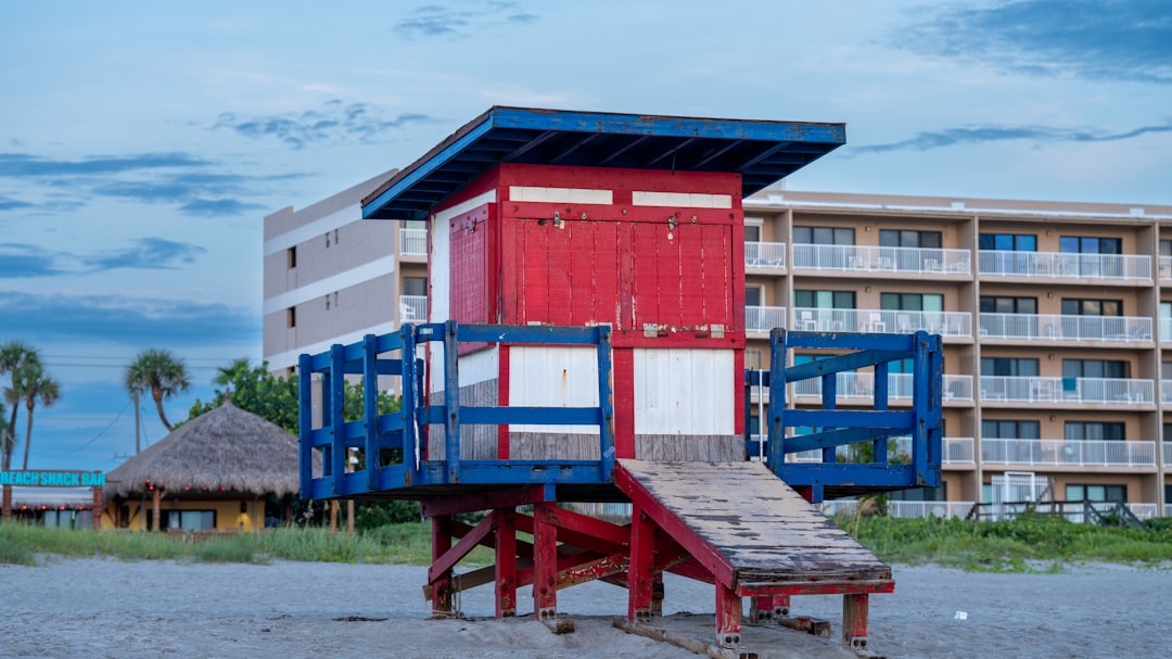 A red and blue lifeguard tower next to a building