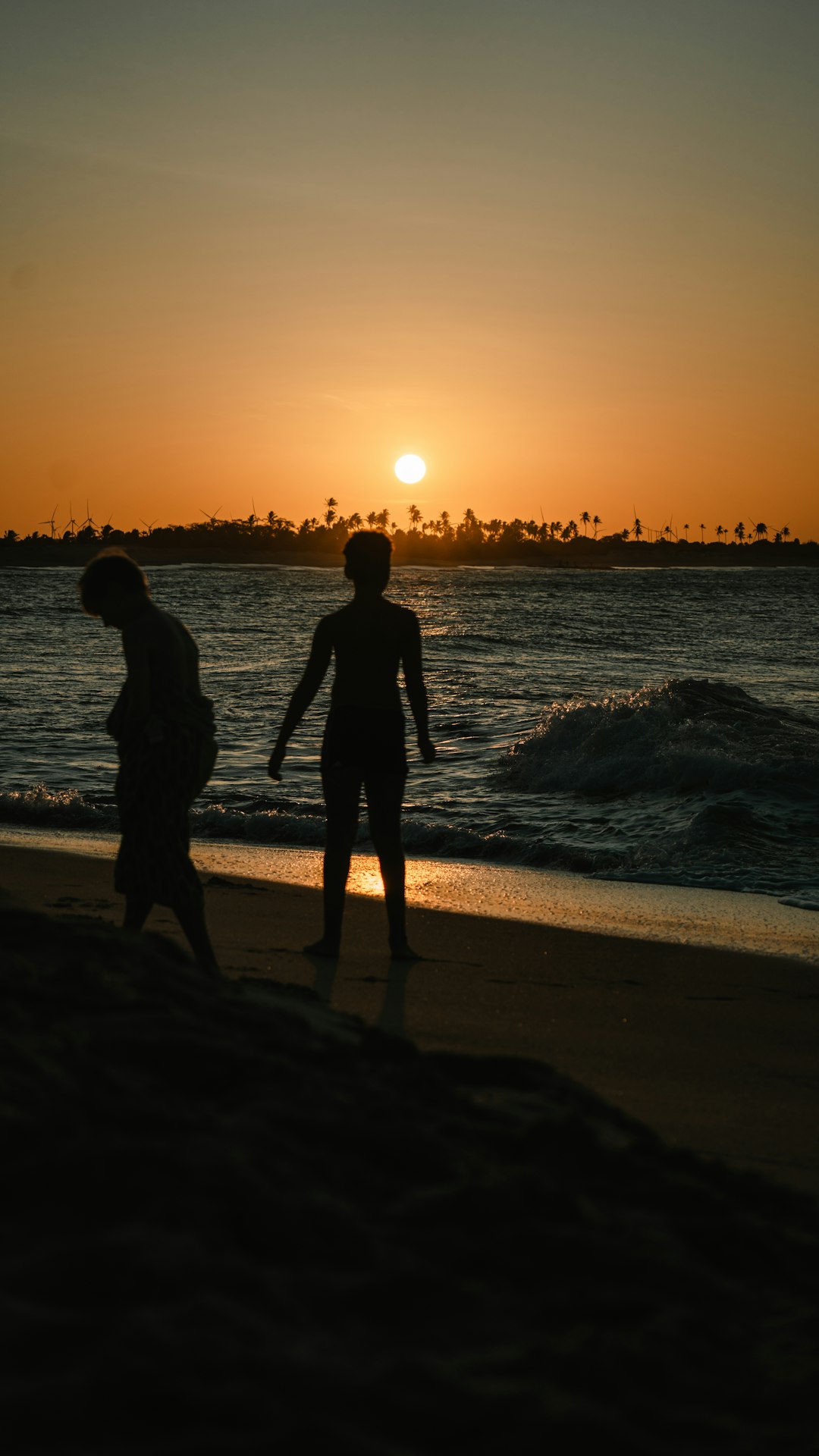 A couple of people standing on top of a beach