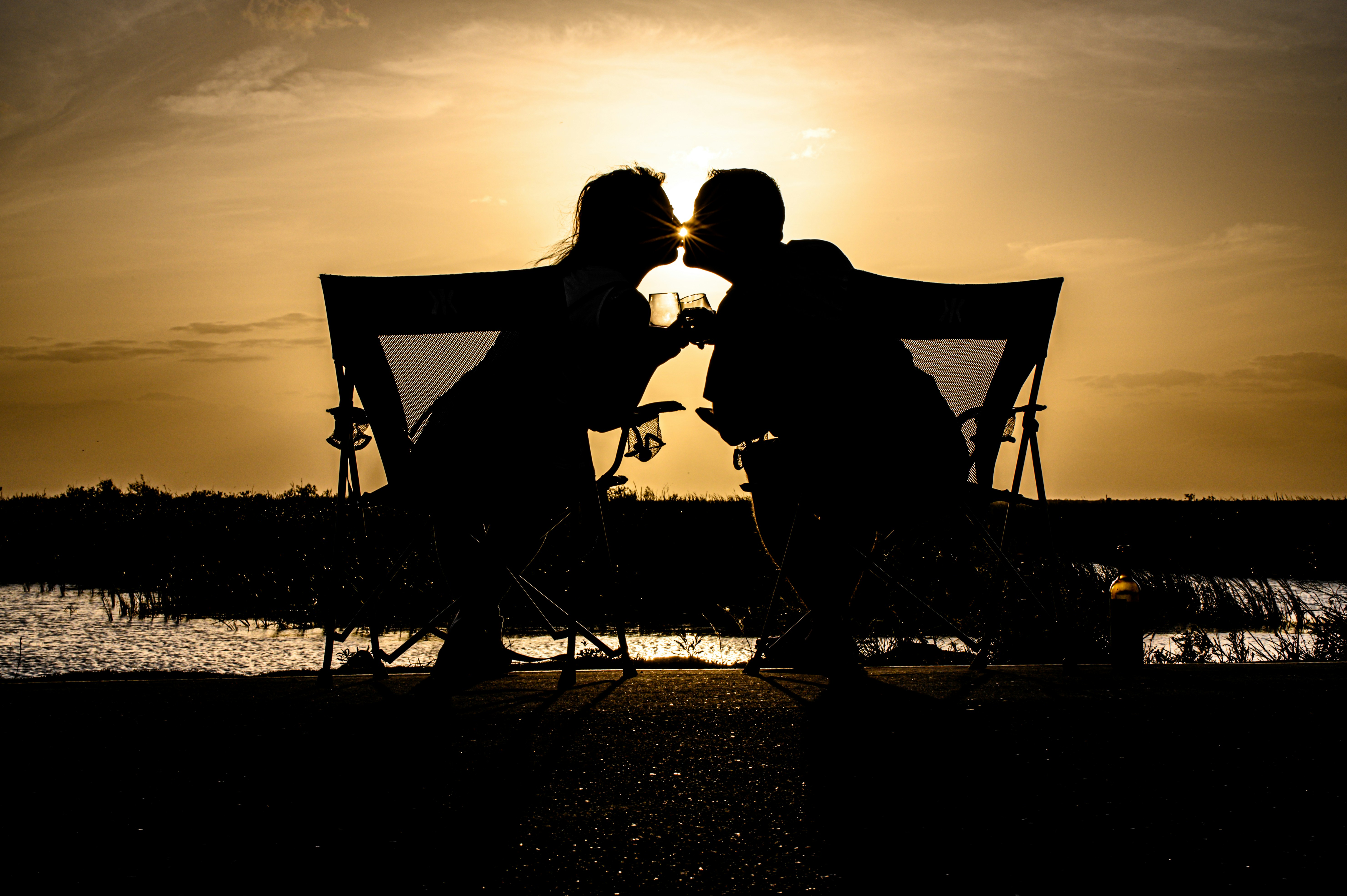a couple of people sitting on a bench with a canopy and a sunset