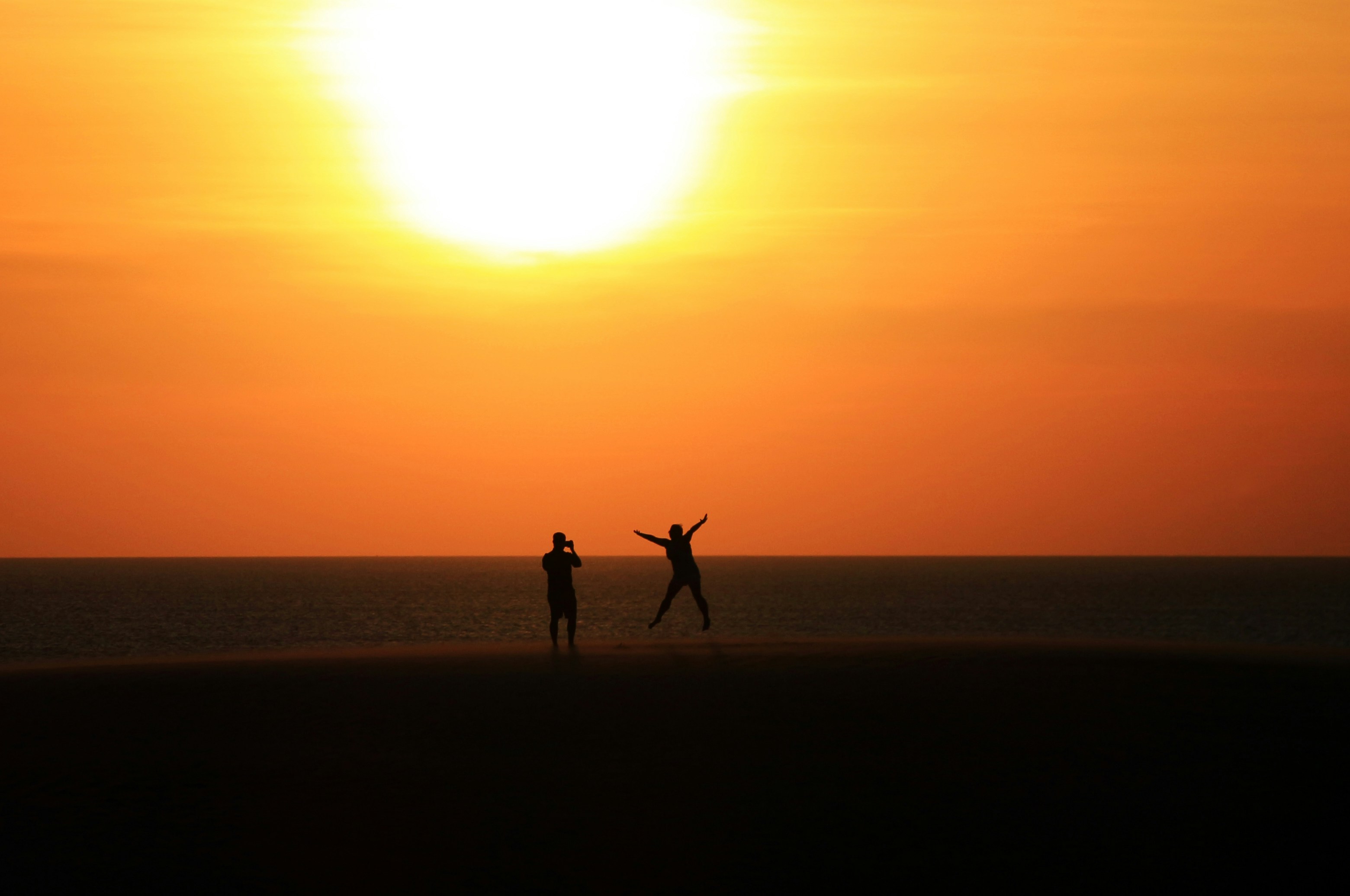 A couple of people standing on top of a beach